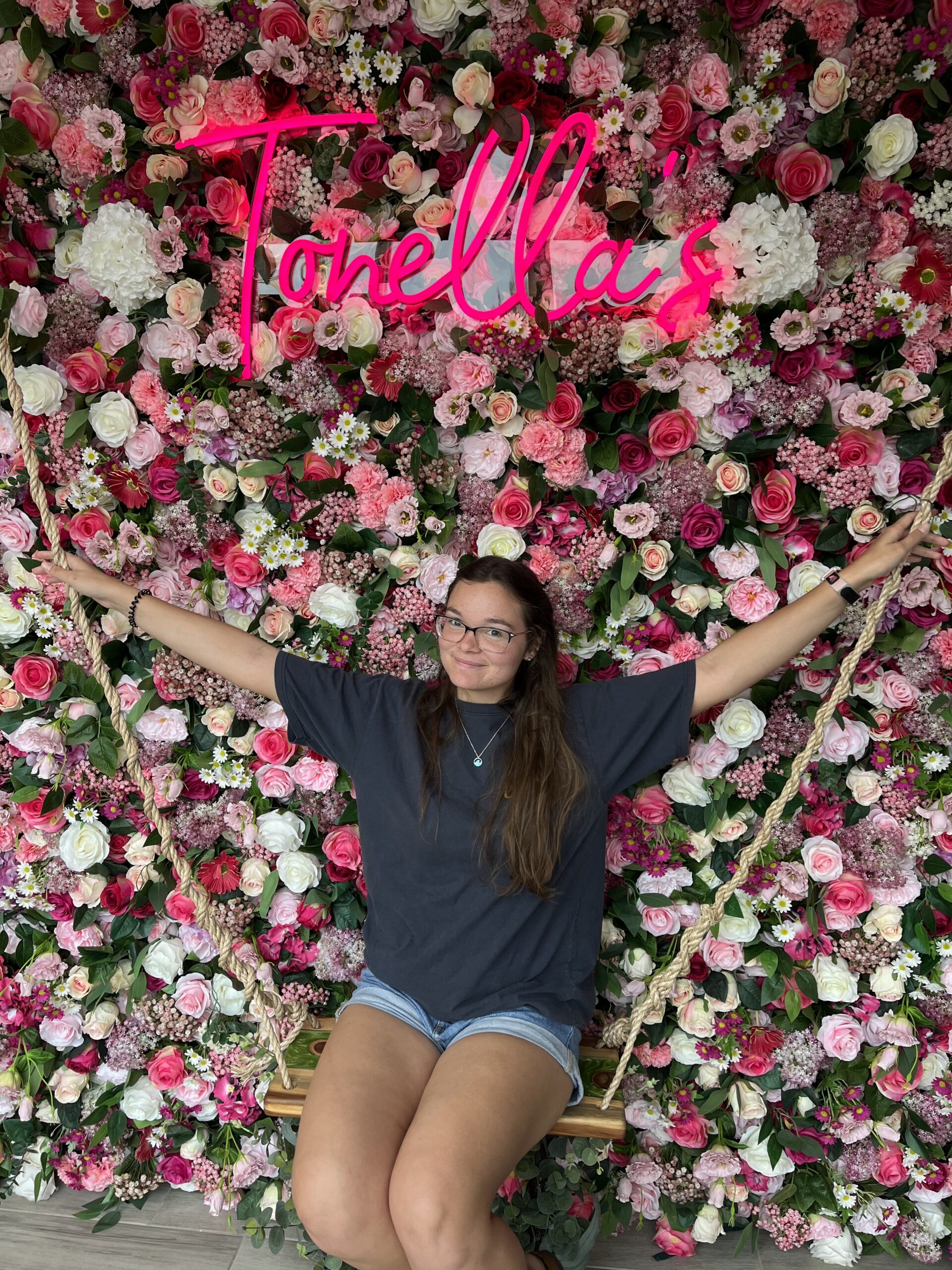 Tiffani Sitting on a swing infant of a wall of flowers